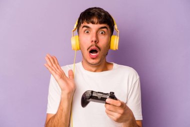 Mor arka planda izole edilmiş bir bilgisayar oyunu kontrolörüyle oynayan İspanyol genç adam şaşırdı ve şok oldu..