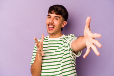 Mor arka planda izole genç beyaz adam kameraya sarıldığı için kendinden emin hissediyor..