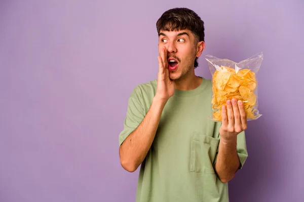 Jonge Spaanse Man Met Chips Geïsoleerd Paarse Achtergrond Zegt Een — Stockfoto