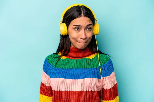 Jonge Spaanse Vrouw Luisteren Naar Muziek Geïsoleerd Blauwe Achtergrond Verward — Stockfoto