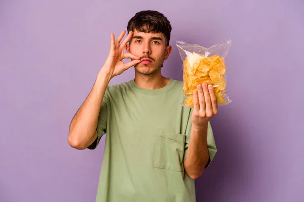 Jonge Spaanse Man Met Chips Geïsoleerd Paarse Achtergrond Met Vingers — Stockfoto