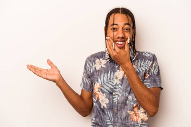 Beyaz arka planda izole edilmiş genç Afro-Amerikalı bir adam avuç içinde fotokopi alanı tutuyor, el üstünde tutuyor. Şaşırmış ve mutlu..