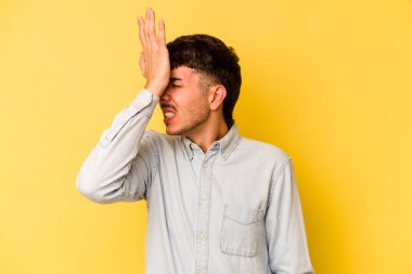 Sarı arka planda izole edilmiş genç beyaz bir adam bir şeyi unutuyor. Alnına avuç içi ve gözlerini kapayarak vuruyor..