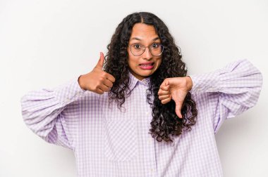 Latin kökenli genç bir kadın beyaz arka planda izole edilmiş, baş parmağını kaldırıyor, zor seçim konsepti.