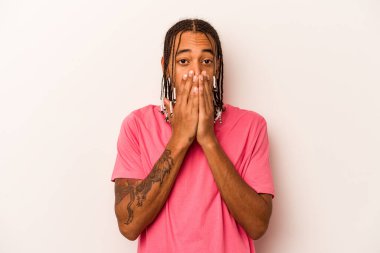 Beyaz arka planda izole edilmiş genç Afrikalı Amerikalı adam elleriyle ağzını kapatırken şok oldu..