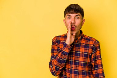 Sarı arka planda izole edilmiş genç beyaz bir adam gizli bir sıcak fren haberi veriyor ve yana bakıyor.