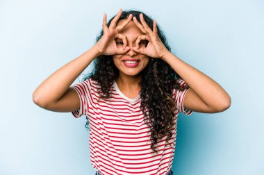 Latin kökenli genç bir kadın mavi arka planda izole edilmiş. Heyecanlı..