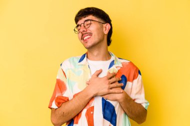 Sarı arka planda izole edilmiş beyaz bir genç, dost canlısı bir ifadeye sahip, avuçlarını göğsüne bastırıyor. Aşk konsepti.