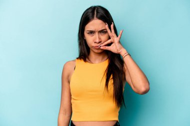 Mavi arka planda izole edilmiş genç İspanyol kadın parmakları dudaklarında bir sır saklıyor..