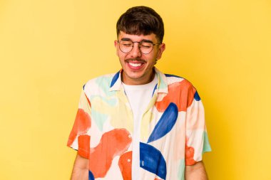 Sarı arka planda izole edilmiş genç beyaz adam gülüyor ve gözlerini kapıyor, rahatlamış ve mutlu hissediyor..