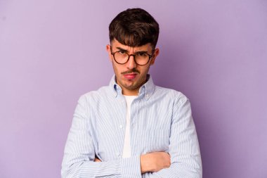 Mor arka planda izole edilmiş genç beyaz adam alaycı bir ifadeyle kameraya bakarken mutsuz oluyor..