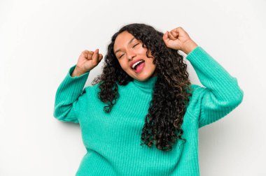 Beyaz arka planda izole edilmiş genç İspanyol kadın özel bir günü kutluyor, atlıyor ve enerjiyle kollarını kaldırıyor..