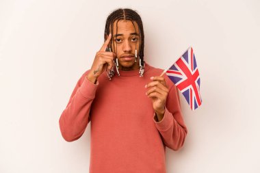 Beyaz arka planda izole edilmiş İngiliz bayrağı tutan genç bir Afro-Amerikan adam parmağıyla tapınağı işaret ediyor, düşünüyor ve bir göreve odaklanıyor..