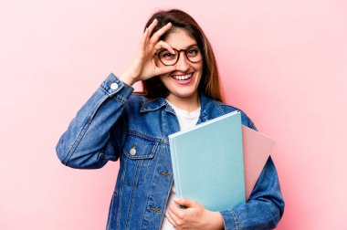 Pembe arka planda izole edilmiş genç beyaz bir kadın heyecanlı..