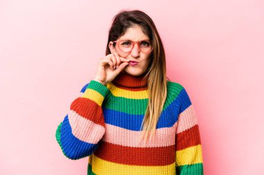 Pembe arka planda izole edilmiş genç beyaz kadın parmakları dudaklarında bir sır saklıyor..