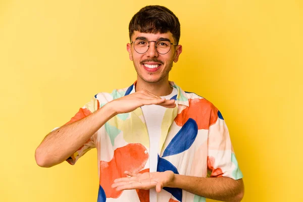 Homem Caucasiano Jovem Isolado Fundo Amarelo Segurando Algo Com Ambas — Fotografia de Stock