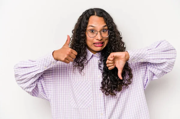Latin kökenli genç bir kadın beyaz arka planda izole edilmiş, baş parmağını kaldırıyor, zor seçim konsepti.