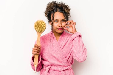 Sırt kaşıyıcısı tutan genç İspanyol kadın beyaz arka planda izole edilmiş, parmakları dudaklarında bir sır saklıyor..