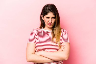 Pembe arka planda soyutlanmış beyaz bir kadın hoşnutsuzca kaşlarını çatmış, kollarını kavuşturmuş..