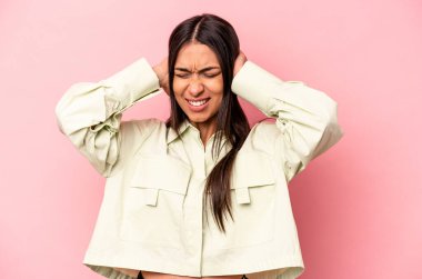 Pembe arka planda izole edilmiş genç İspanyol kadın kulaklarını elleriyle kapatıyor..