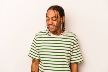 Beyaz arka planda izole edilmiş genç Afrikalı Amerikalı adam gülüyor ve gözlerini kapıyor, rahatlamış ve mutlu hissediyor..