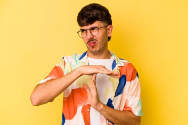 Sarı arka planda izole edilmiş genç beyaz adam bir mola hareketi gösteriyor..