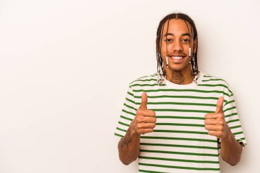 Genç Afrikalı Amerikalı adam beyaz arka planda izole edilmiş gülümsüyor ve başparmağını kaldırıyor.