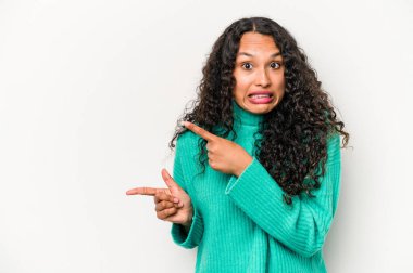 Beyaz arka planda izole edilmiş genç İspanyol kadın işaret parmağıyla fotokopi alanını işaret ederek şok oldu..