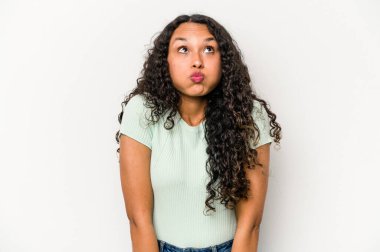 Beyaz arka planda izole edilmiş genç İspanyol kadın omuz silkiyor ve gözleri açık..