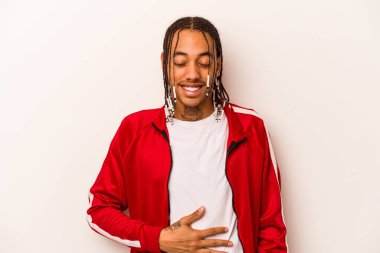 Beyaz arka planda izole edilmiş genç Afrikalı Amerikalı adam karnına dokunuyor, nazikçe gülümsüyor, yemek yiyor ve tatmin oluyor..