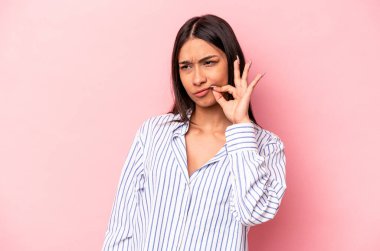 Pembe arka planda izole edilmiş genç İspanyol kadın parmakları dudaklarında bir sır saklıyor..