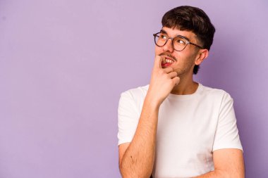 Mor arka planda izole edilmiş genç beyaz adam rahatlamış bir şeyin fotokopi odasına baktığını düşünüyor..
