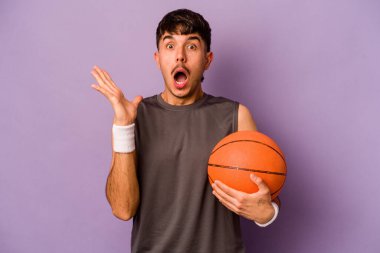 Genç İspanyol basketbolcu. Mor arka planda izole edilmiş. Şaşırmış ve şok olmuş..