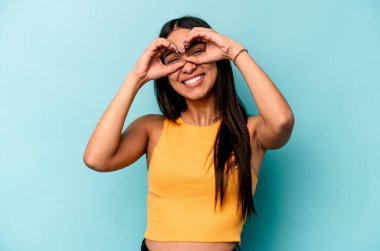 Mavi arka planda izole edilmiş genç İspanyol kadın gözlerinde sorun olmadığını gösteriyor.