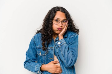 Beyaz arka planda izole edilmiş genç İspanyol kadın yanakları patlatıyor, yorgun bir ifadesi var. Yüz ifadesi kavramı.