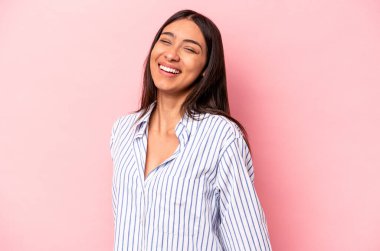 Pembe arka planda izole edilmiş genç İspanyol kadın gülüyor ve gözlerini kapıyor, rahatlamış ve mutlu hissediyor..