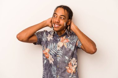 Genç Afrikalı Amerikalı bir adam beyaz arka planda izole edilmiş, kendinden emin, elleri başının arkasında..