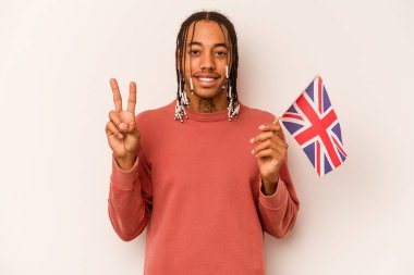Beyaz arka planda iki numarayı parmaklarıyla gösteren İngiliz bayrağı tutan genç bir Afro-Amerikan..
