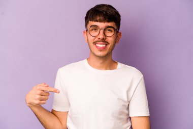 Mor arka planda izole olmuş genç beyaz bir adam gömlek fotokopisini elle gösteriyor, gururlu ve kendinden emin.