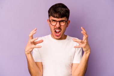 Mor arka planda izole edilmiş genç beyaz adam öfkeyle bağırıyor..