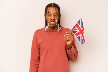 Beyaz arka planda izole edilmiş İngiliz bayrağı tutan genç Afro-Amerikan bir adam çok sinirli ve agresif bağırıyor..