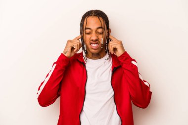 Genç Afrikalı Amerikalı bir adam beyaz arka planda izole edilmiş parmaklarıyla kulaklarını kapatan, yüksek sesli bir ortam tarafından stresli ve umutsuz..
