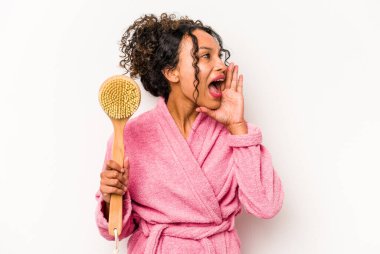 Beyaz arka planda izole edilmiş sırt kaşıyıcı tutan genç İspanyol kadın bağırıyor ve avuç içini açık tutuyor..