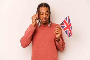 Elinde İngiliz bayrağı olan genç bir Afrikalı Amerikalı adam beyaz arka planda izole edilmiş kulakları elleriyle kapatıyor..