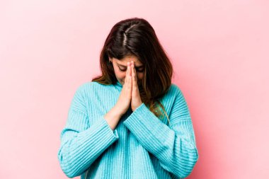 Pembe arka planda izole edilmiş genç beyaz kadın dua ediyor, bağlılık gösteriyor, dindar biri ilahi ilham arıyor..