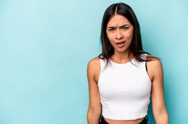 Mavi arka planda izole edilmiş genç İspanyol kadın çok kızgın, öfkeli, hayal kırıklığına uğramış.