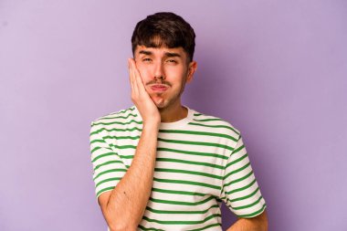 Mor arka planda izole edilmiş genç beyaz adamın yanakları şişer, yorgun bir ifadesi vardır. Yüz ifadesi kavramı.