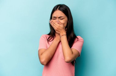 Mavi arka planda izole edilmiş genç İspanyol kadın virüs ya da enfeksiyon yüzünden boğaz ağrısı çekiyor..