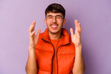 Mor arka planda izole olmuş genç beyaz adam yüksek sesle gülüyor elini göğsüne koyuyor..