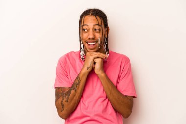 Beyaz arka planda izole edilmiş genç Afrikalı Amerikalı ellerini çenesinin altında tutuyor ve mutlu bir şekilde yan tarafa bakıyor..